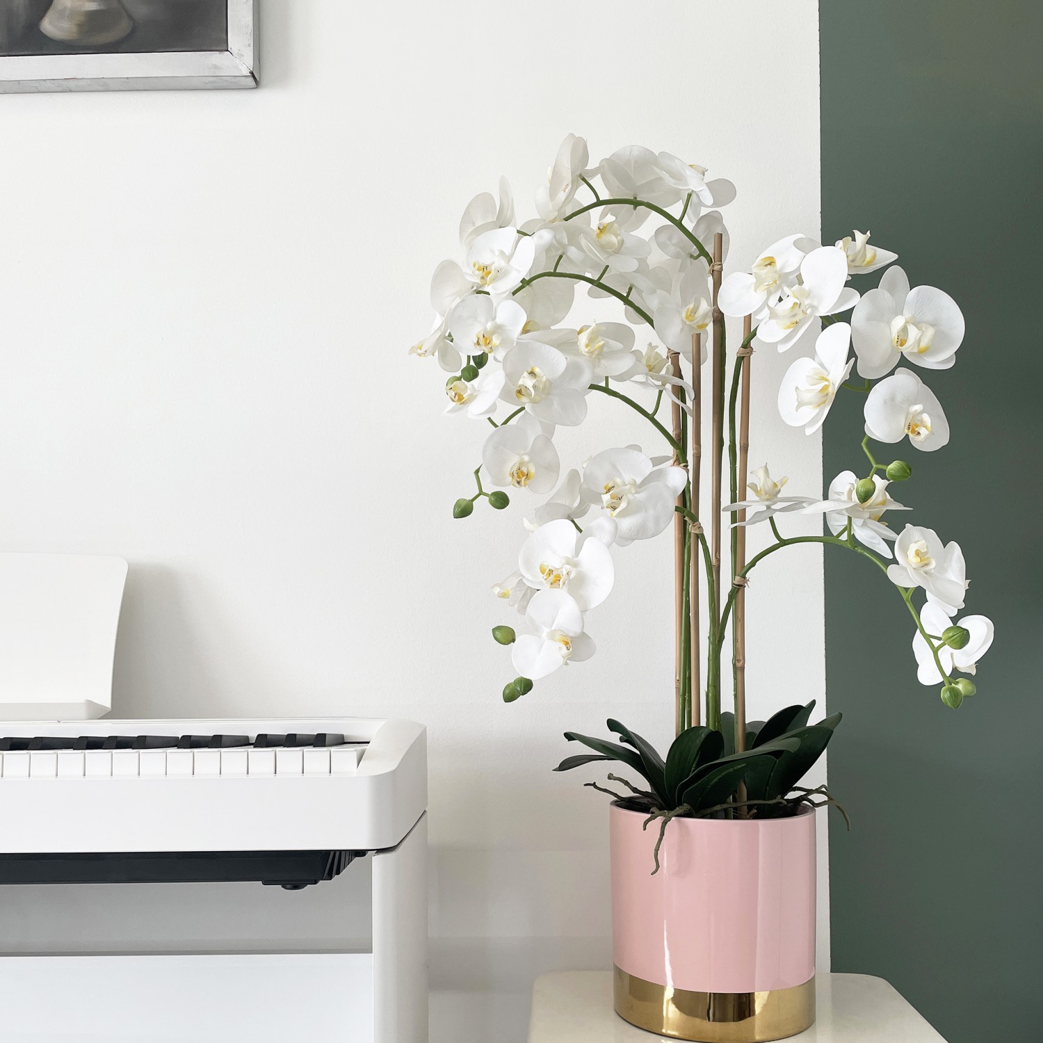 Orchidées artificielles pot rose et or 80cm en ambiance surélevé à côté d'un piano blanc