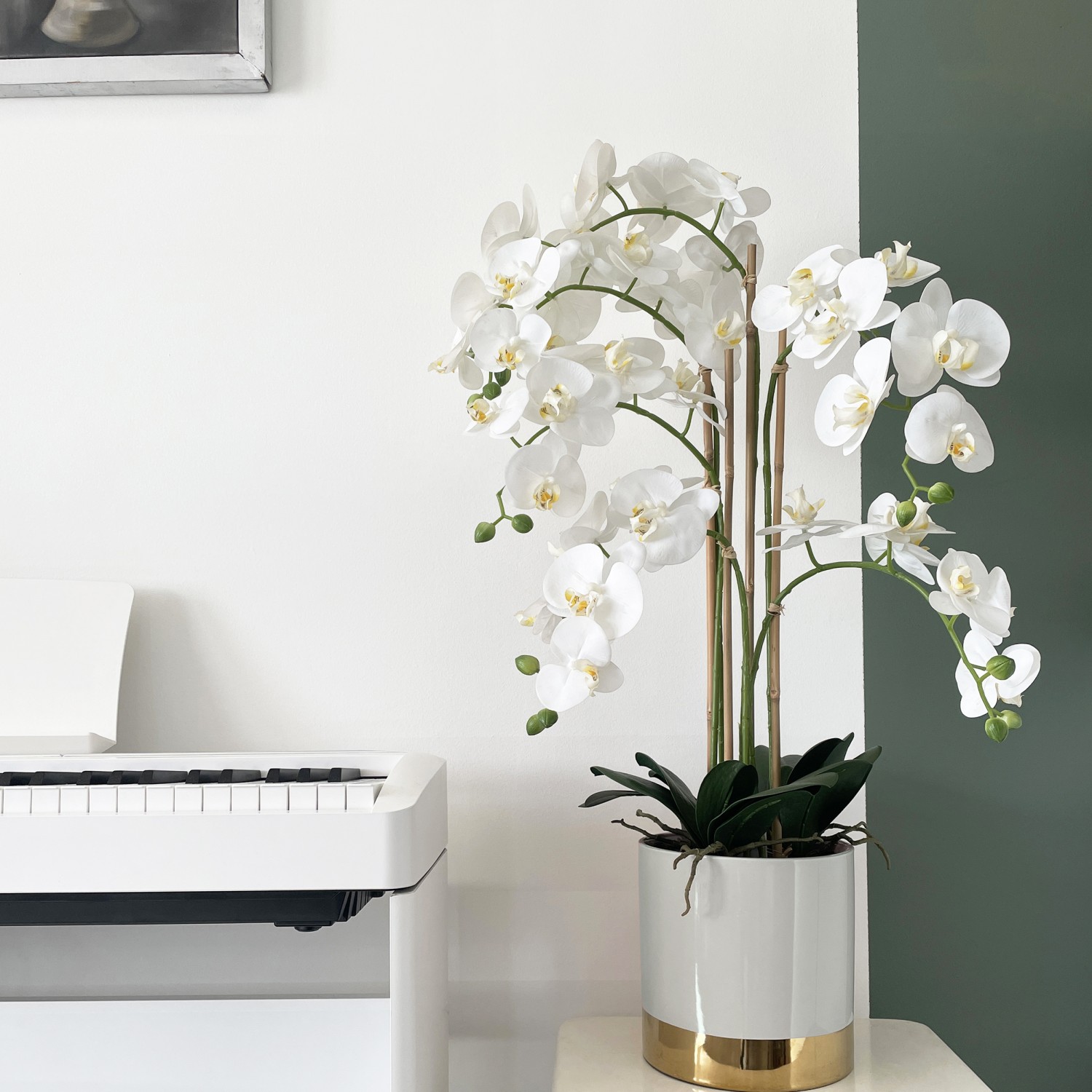 Orchidées artificielles pot gris et or 80cm en ambiance surélevé à côté d'un piano blanc