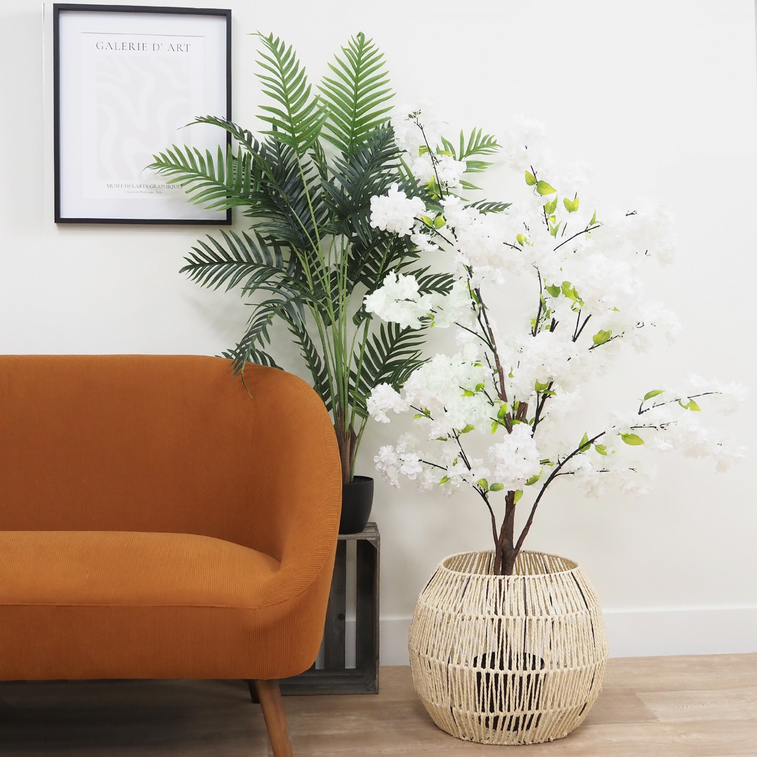 Cerisier artificiel blanc 130cm en ambiance avec un palmier à côté d'un canapé