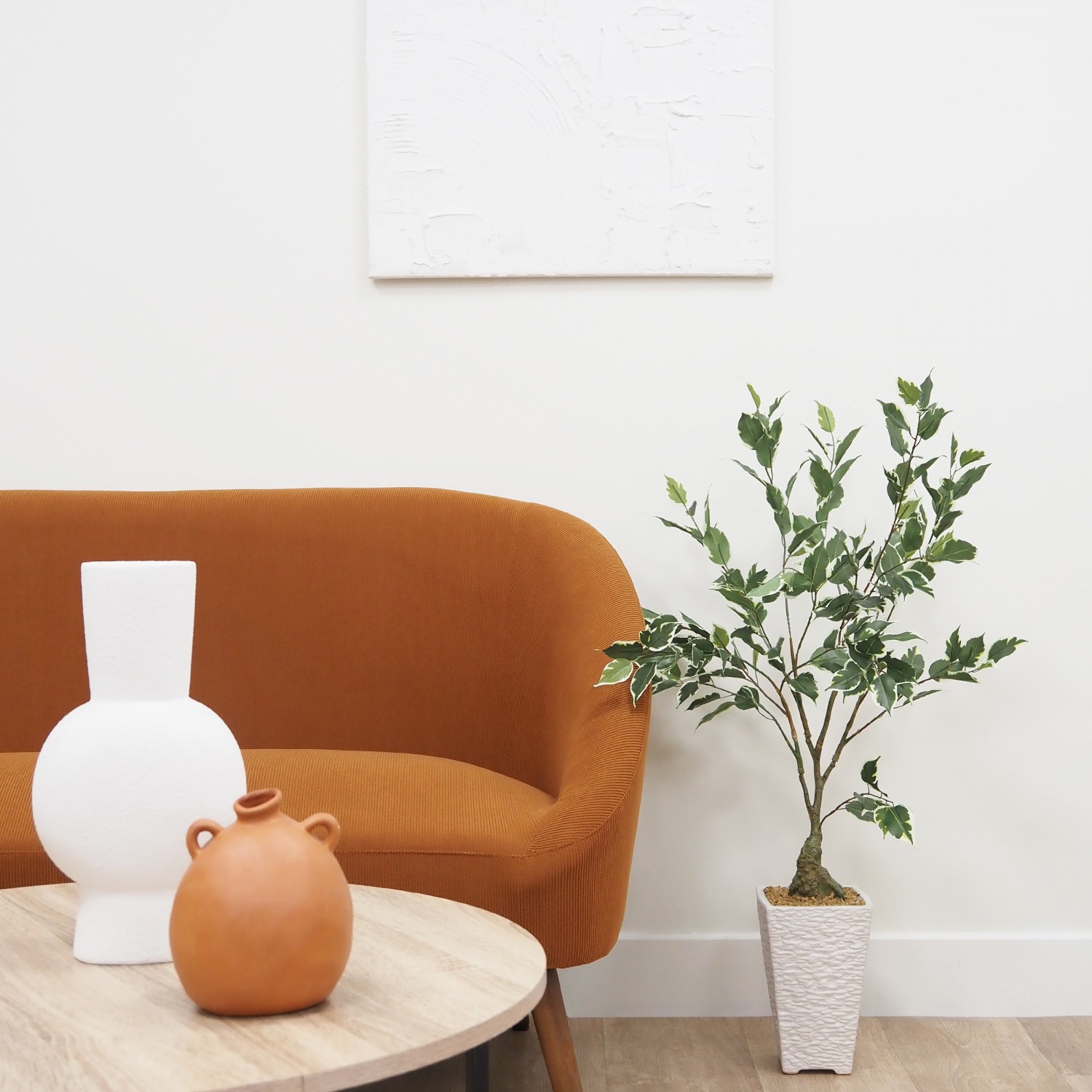 Ficus artificiel panaché 100cm posé à côté d'un canapé