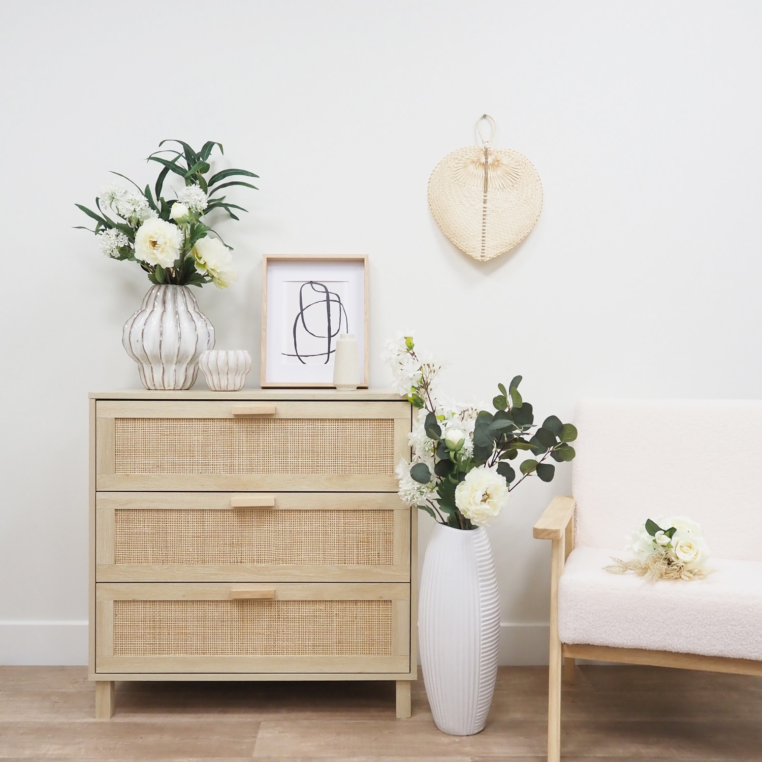 Pivoine artificielle en tige blanche 70cm lot de 4 dans un vase posé entre une commode et un fauteuil