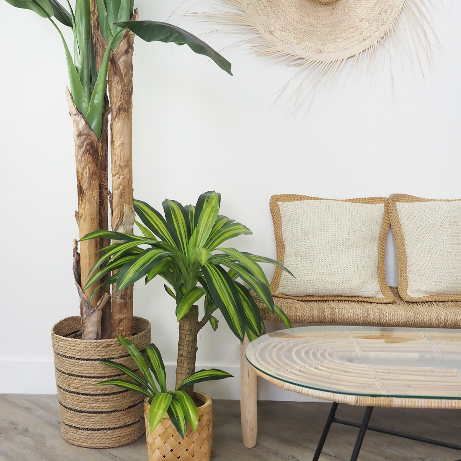 Dracena artificiel toucher naturel 80cm posé dans un cache-pot à côté d'un grand bananier et d'une table