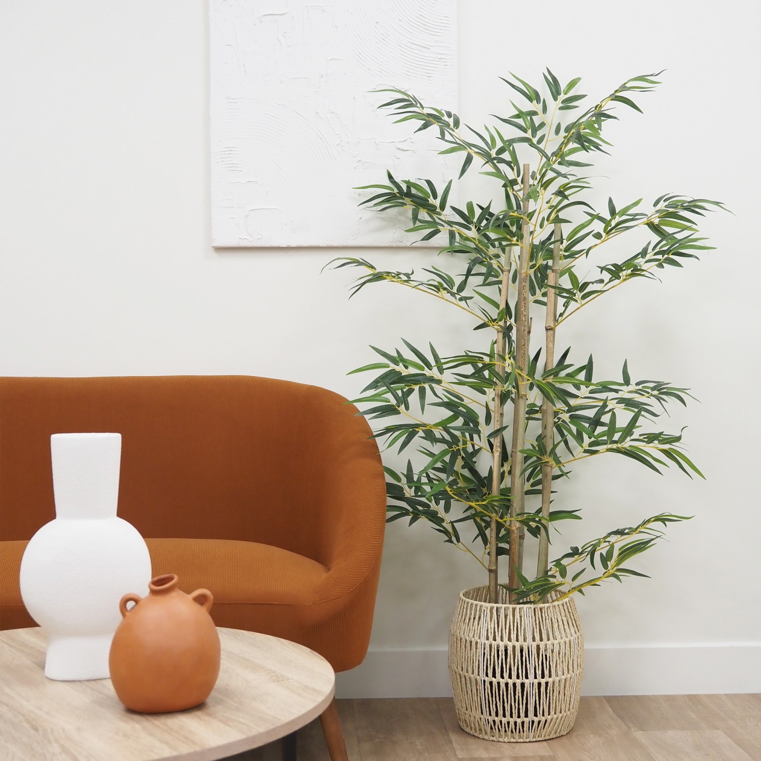 Bambou artificiel 612 feuilles 150cm posé dans un cache-pot à côté d'un canapé