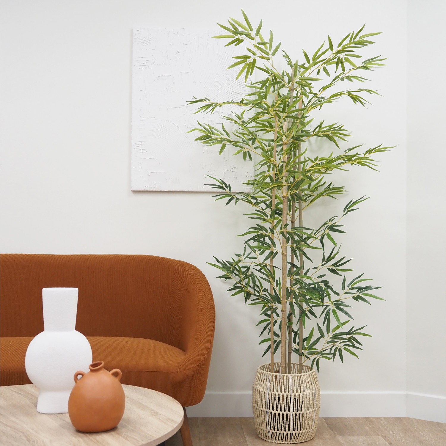 Bambou artificiel 838 feuilles 180cm posé dans un cache-pot à côté d'un canapé