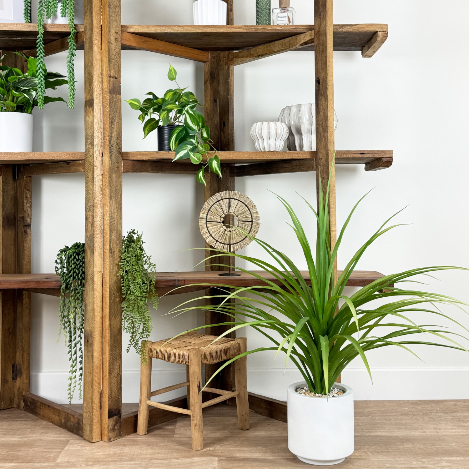 Dracena artificiel 95cm posé devant des étagères avec de la déco