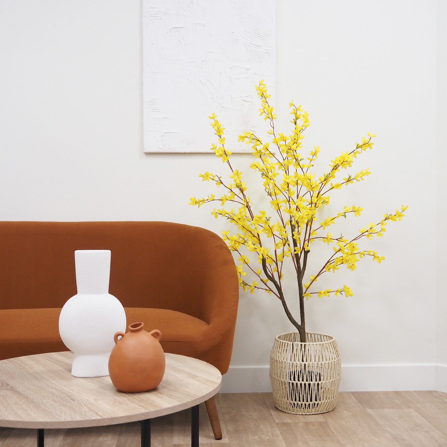 Forsythia artificiel jaune 150cm posé dans un cache-pot à côté d'un canapé
