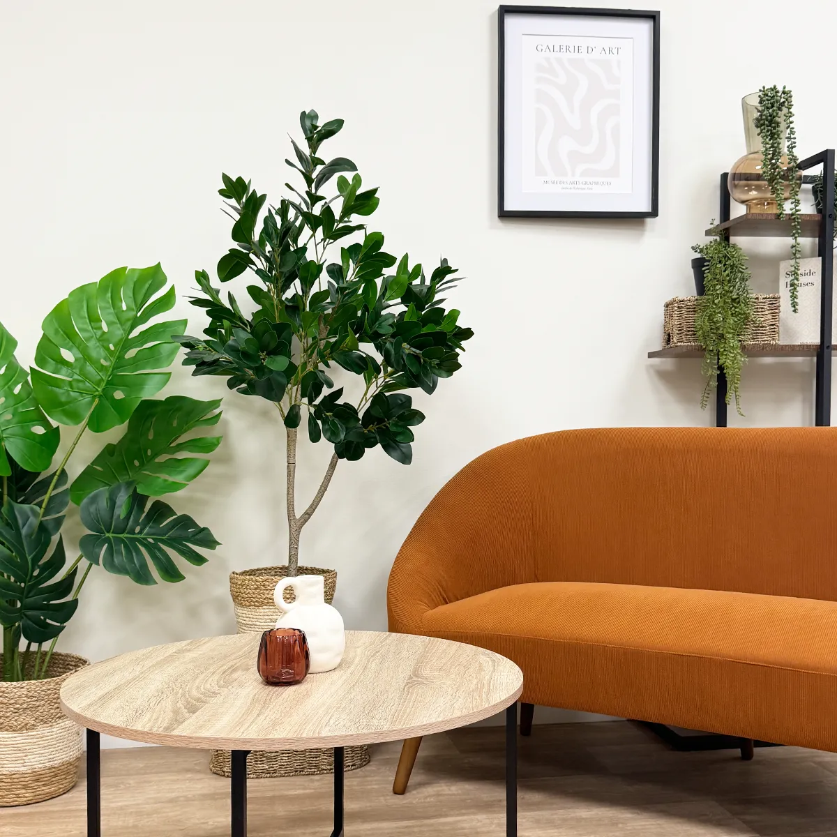 Laurier artificiel 328 feuilles 120cm posé avec d'autres plantes artificielles à côté d'un canapé